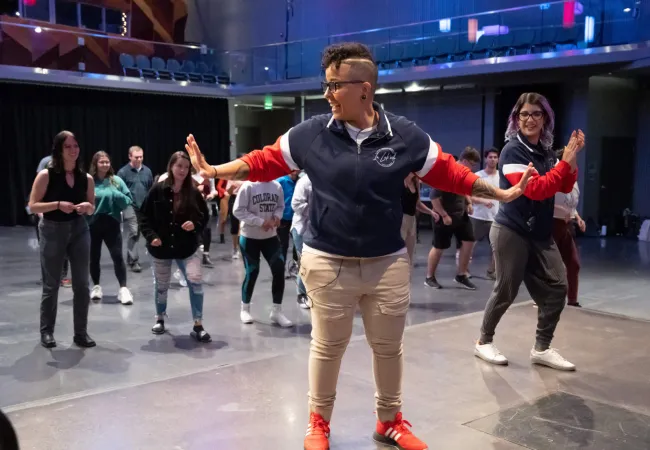 Someone from El Centro teaching dance moves to a group of students