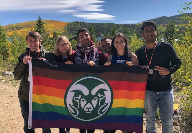 Pride students holding a CSU Pride flag together outside