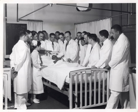 A historical photo of doctors and medical staff surrounding a patient