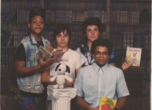 Four young people holding children's books and a Snoopy doll